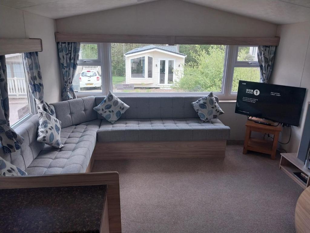 a living room with a couch and a television at Tree tops - 2 bedroom static caravan with decking in Hastings