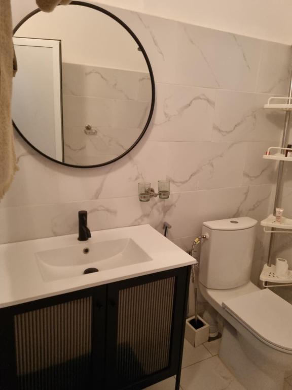 y baño con lavabo, espejo y aseo. en La villa Lisbonne, en Somone