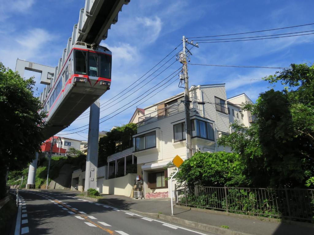 a train on a bridge over a street with a house at Hostel Kamakura in Kamakura