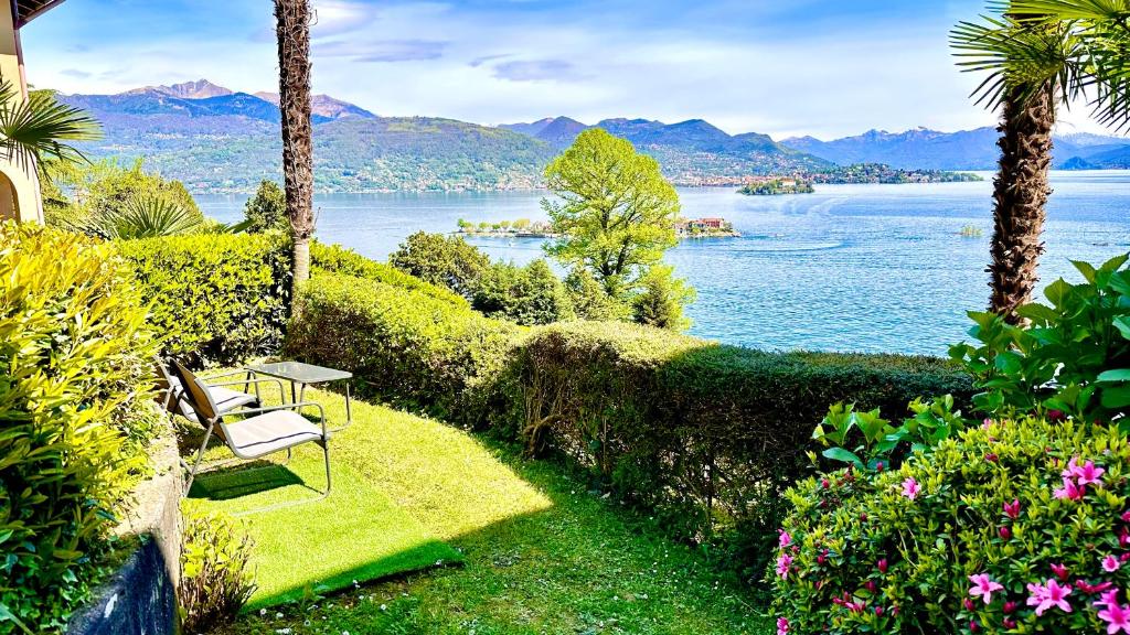 einen Garten mit einem Tisch und Stühlen sowie Seeblick in der Unterkunft Appartamento Marina in Stresa