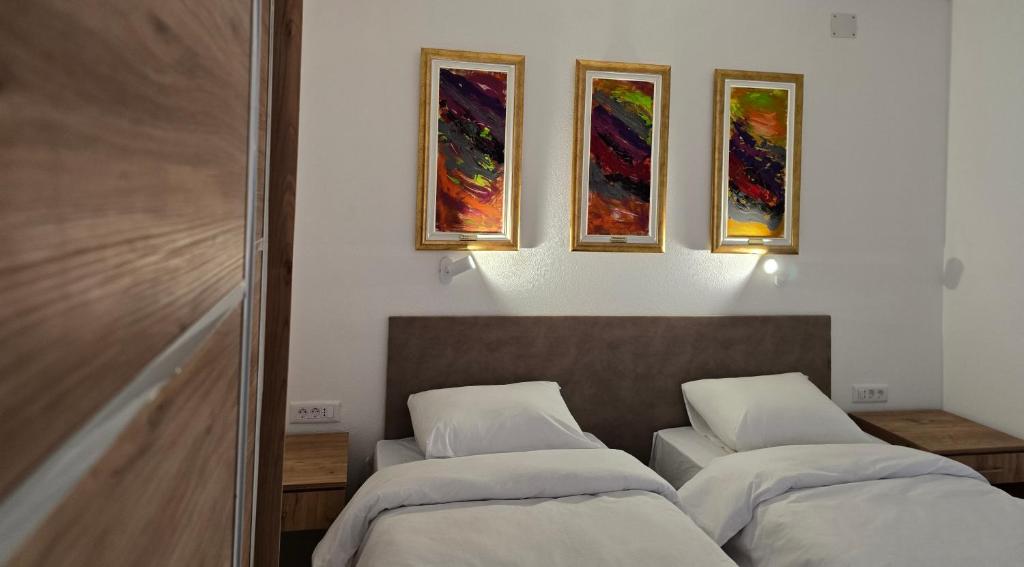 two beds in a room with paintings on the wall at Mayberry Highway - Apartmani Medijapark in Sveti Nikole