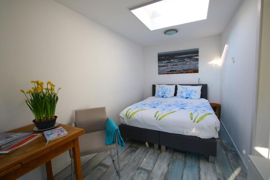 a bedroom with a bed and a desk and a chair at Studio Eb in Egmond aan Zee