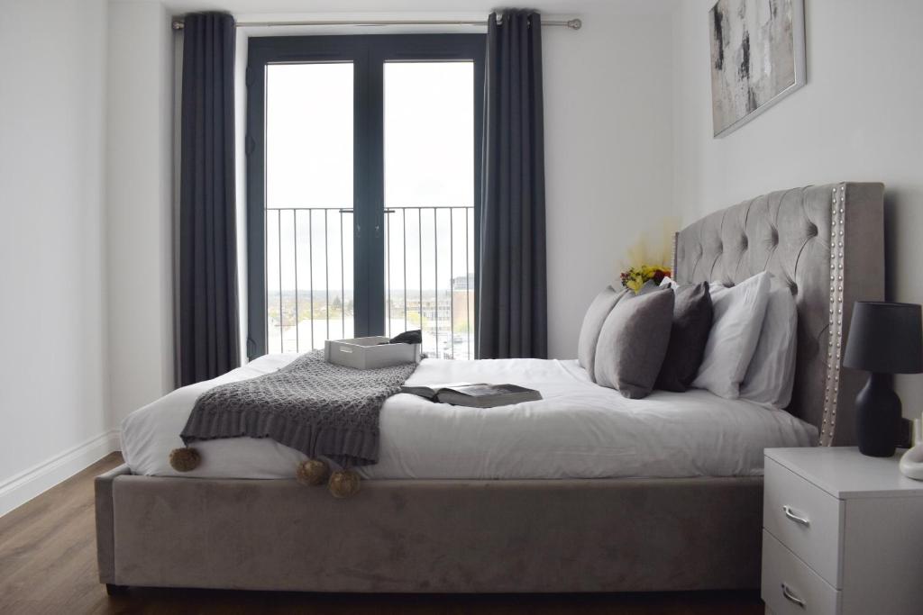 um quarto com uma cama grande e uma janela grande em Beautiful two bedroom with balcony in Brentwood em Brentwood
