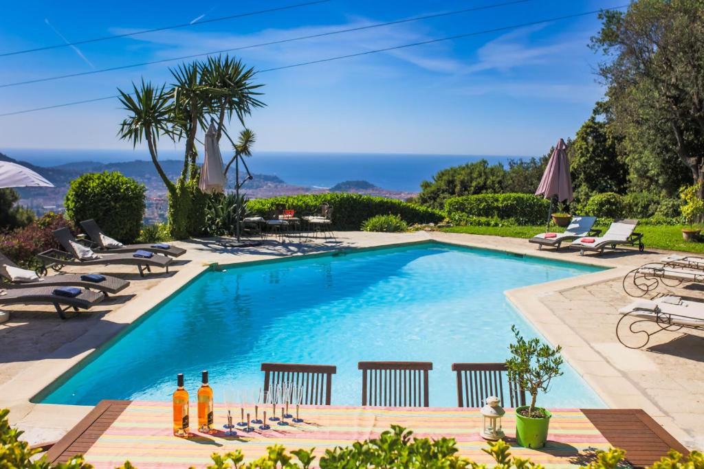 - une piscine avec des chaises longues et des parasols dans l'établissement LOU MAS SOUBRAN VI2083 by RIVIERA HOLIDAY HOMES, à Nice