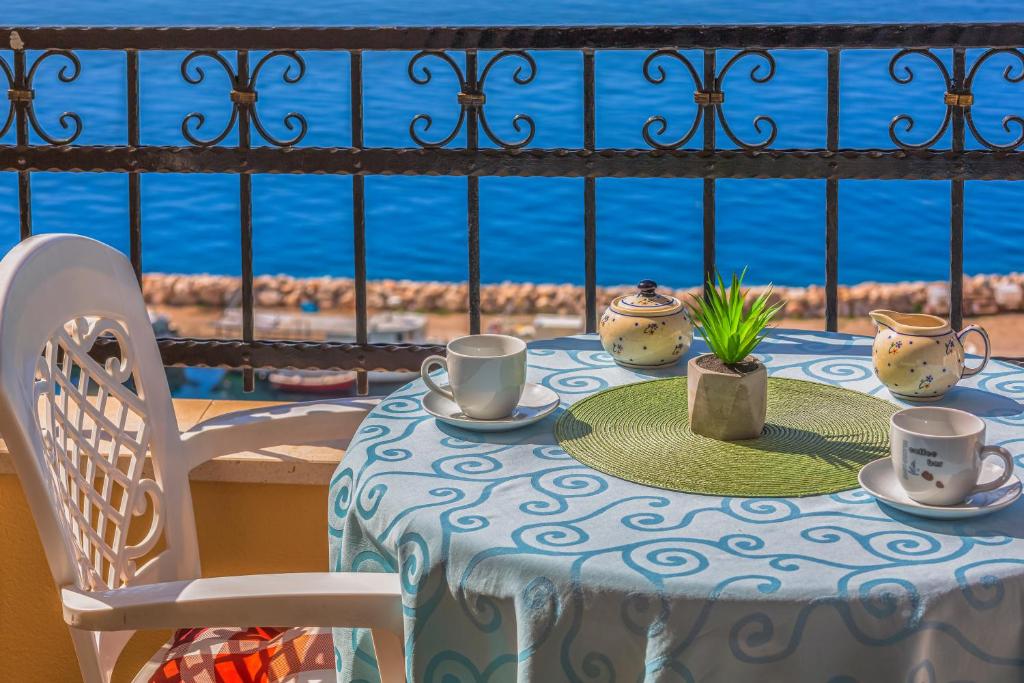 a table with cups and saucers on it with a view of the ocean at Apartments Gudelj in Podgora