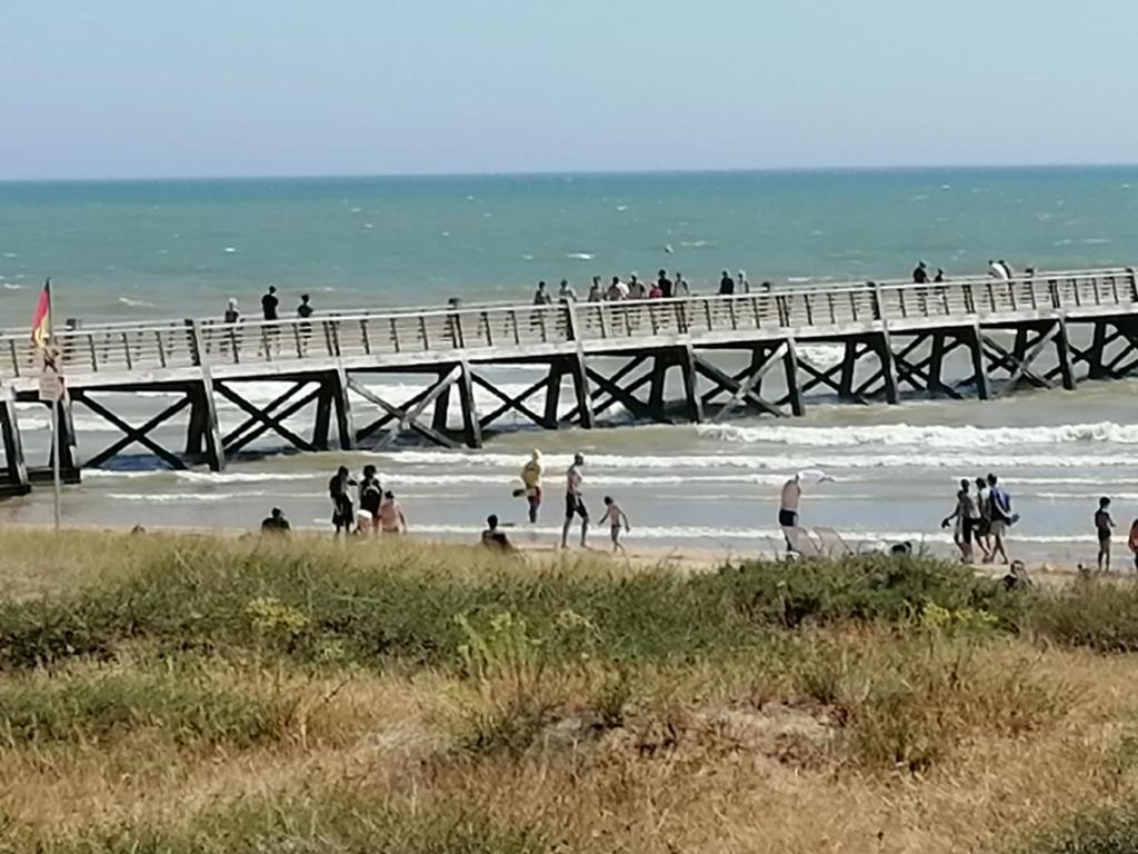 a group of people on the beach near a pier at Domaine de la lumière in Saint-Jean-de-Monts
