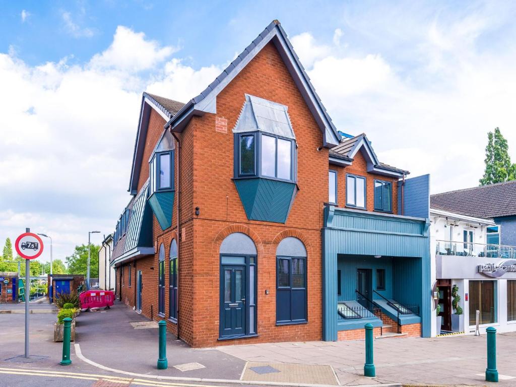 a red brick building with a balcony on a street at The Ecclesian Deluxe Apartments near Trafford Centre Eccles Train Station in Manchester