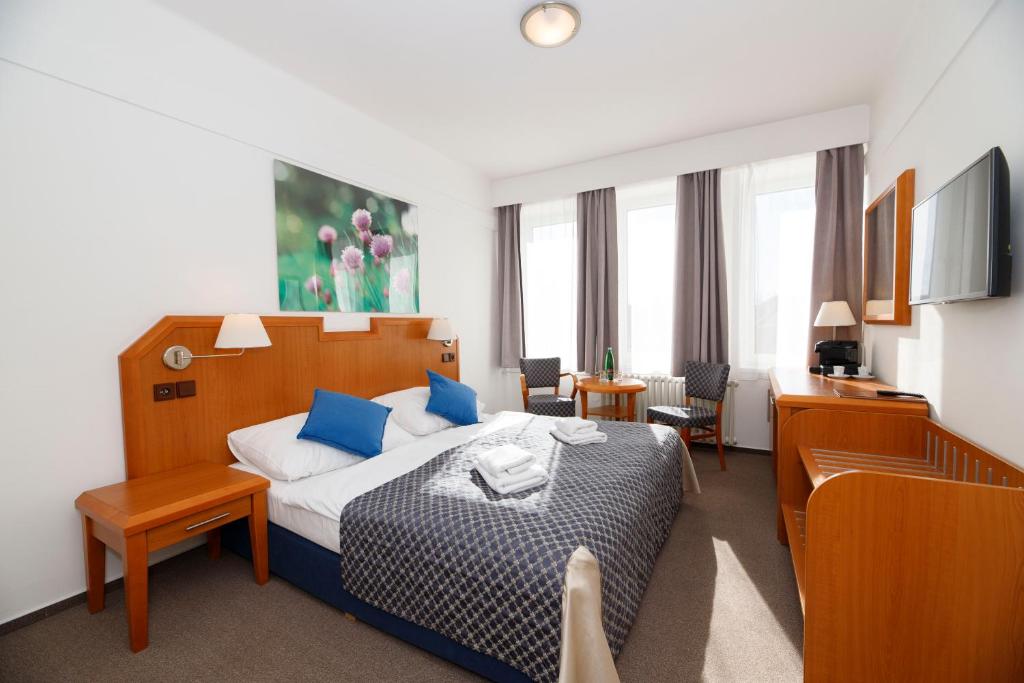 クトナー・ホラにあるLH Hotel Mědínek Old Townのベッドとデスクが備わるホテルルームです。