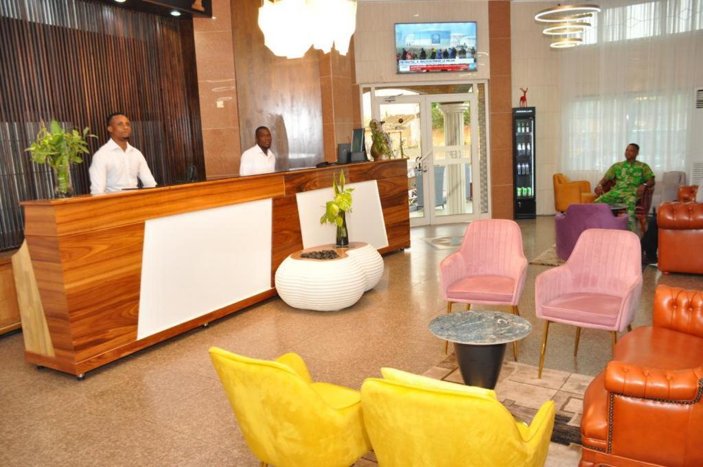 una hall con sedie colorate e una reception di Freedom Palace Hôtel a Porto-Novo