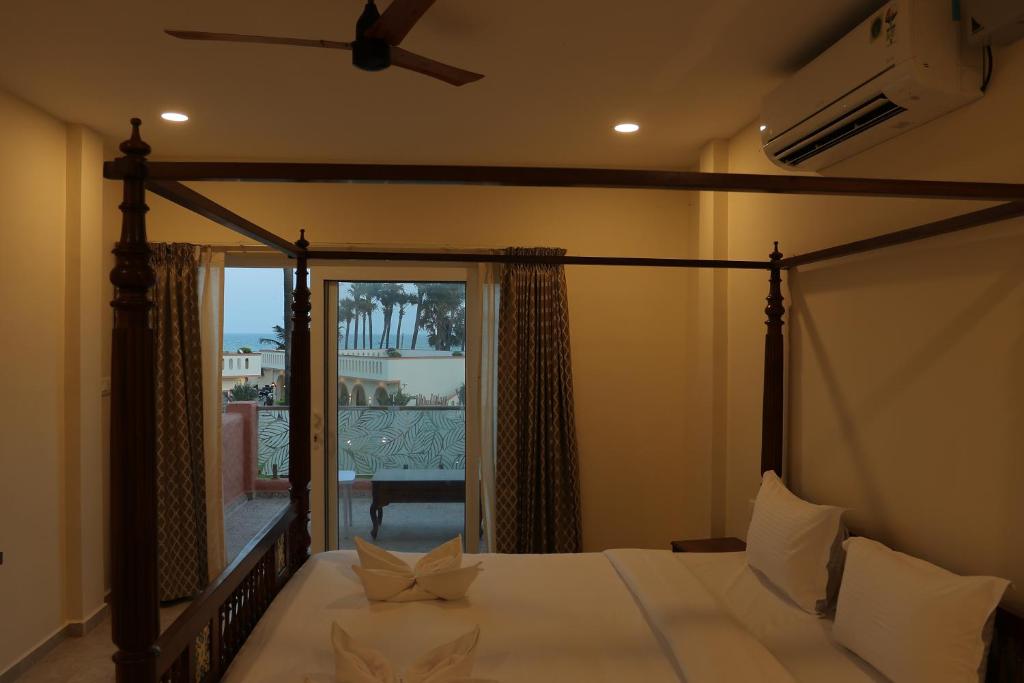 een slaapkamer met een hemelbed en een groot raam bij PALM PARADISE Beach Resort in Pondicherry