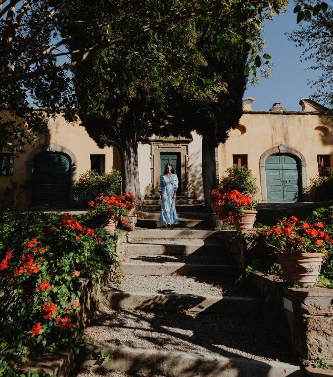 kobieta stojąca przed domem z kwiatami w obiekcie Il Falconiere Relais & Spa w mieście Cortona