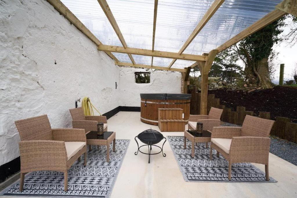 a patio with chairs and a table and a grill at Dundrine Cottage in Maghera