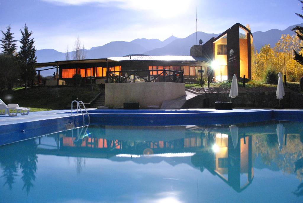 a house with a swimming pool in front of a house at Pueblo Del Rio Mountain Lodge & Spa in Potrerillos