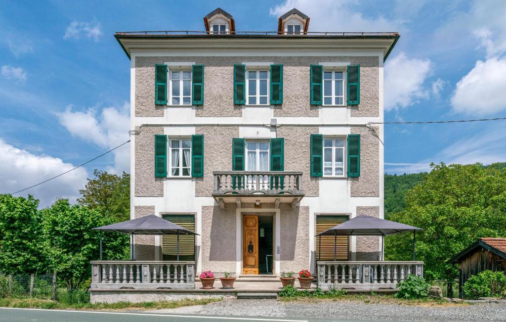 Casa grande con puertas y ventanas con persianas verdes en 1 Bedroom Pet Friendly Apartment In Loco Di Rovegno, en Torriglia