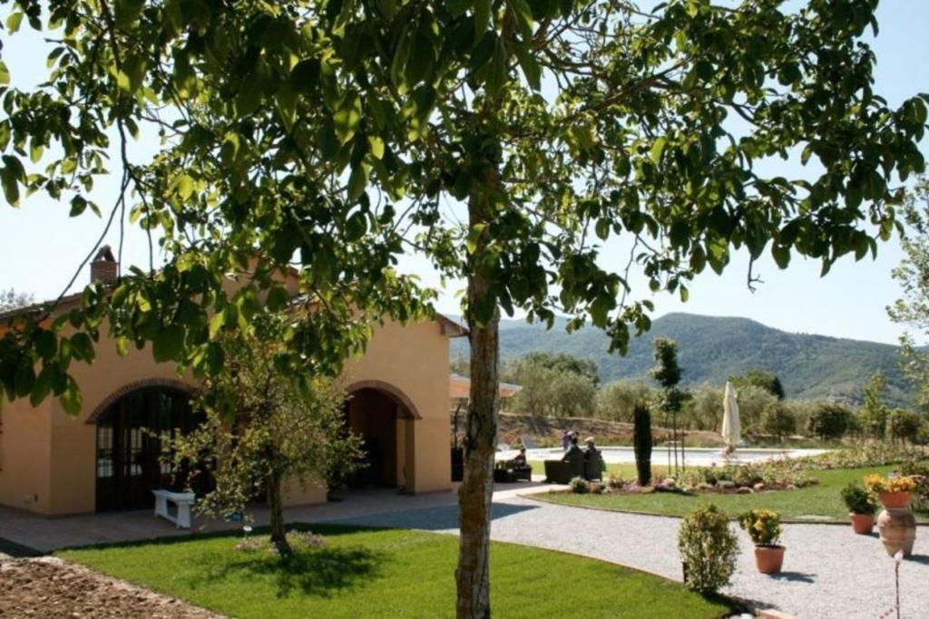 ein Gebäude mit einem Garten mit einem Baum im Vordergrund in der Unterkunft Villa Fiorentina in Castiglion Fiorentino