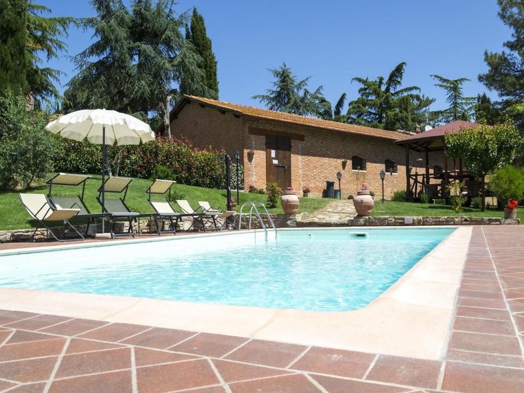 a pool with chairs and an umbrella next to a house at Villa Camelia in Cortona