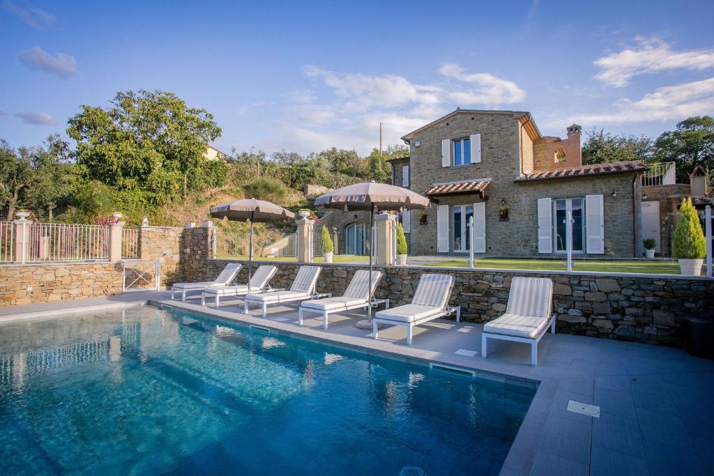 a swimming pool with chairs and a house at Villa Chiara in Cortona