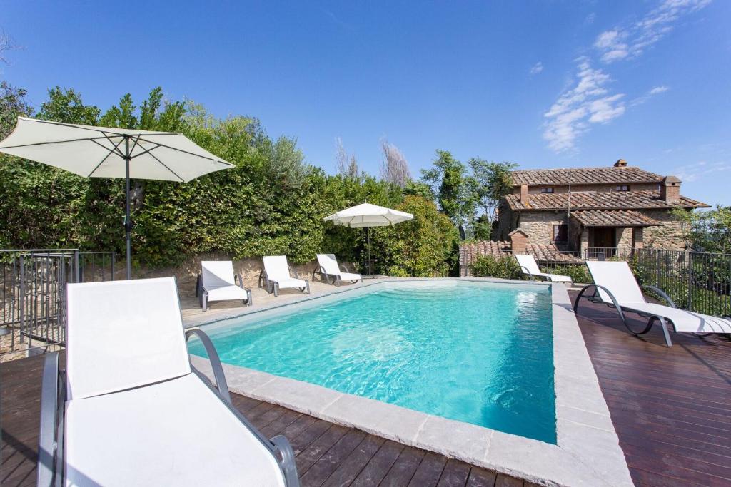 a swimming pool with chairs and an umbrella at Villa I Cocciai in Cortona