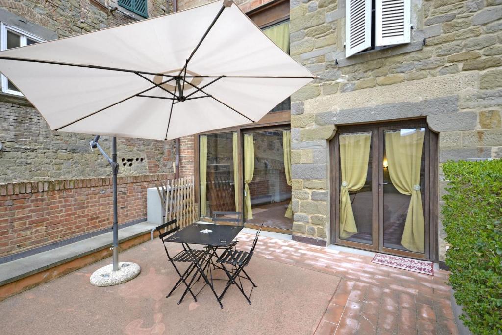 una mesa y una sombrilla blanca frente a un edificio en Appartamento Passerini, en Cortona