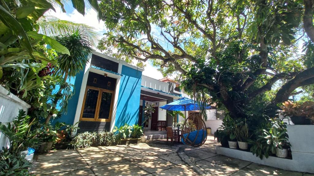 ein blaues Haus mit einem Baum davor in der Unterkunft Nusawiru Guest House in Pangandaran