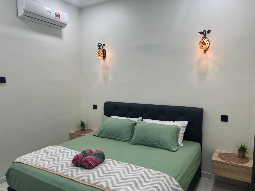 a bedroom with a bed with two lamps on the wall at Padang Besar Syaripah Homestay in Padang Besar