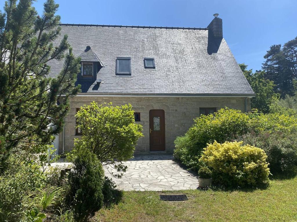 una casa de piedra con una puerta roja y algunos arbustos en 102 - Belle Maison Familiale dans quartier calme, en Fréhel
