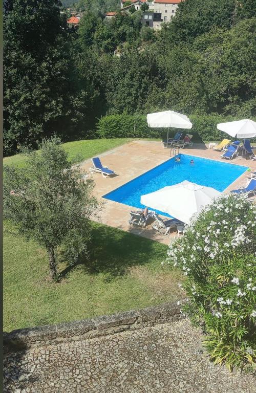 a large swimming pool with chairs and umbrellas at Gerês - Aldeia Turística de Louredo in Vieira do Minho