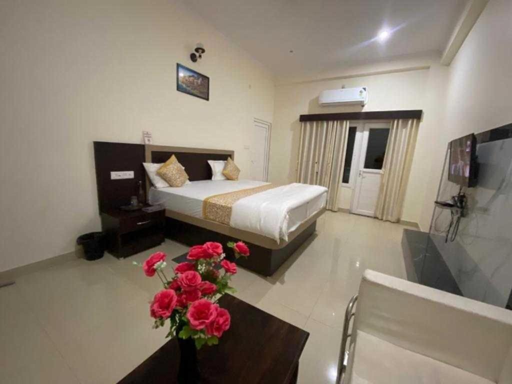 a bedroom with a bed and a table with flowers at Hotel Nath Palace Chunar Road Varanasi - Luxury Room - Excellent Service Recommended in Varanasi