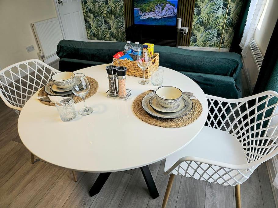 HeeleyにあるAbbeydale Place-Spacious one bedroom flatの白いテーブル(椅子2脚付)、テーブル(カップ、皿付)