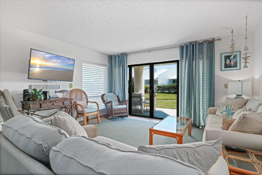 a living room with a couch and a table at Ground floor beachfront with steps to the beach and pool & beach access in New Smyrna Beach