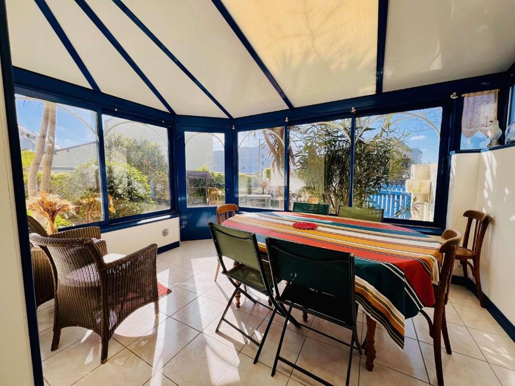 a dining room with a table and chairs and windows at Maison 4P, 95m², cœur de Quiberon, proche plage, jardin sud, WIFI, 8 pers - FR-1-478-278 in Quiberon