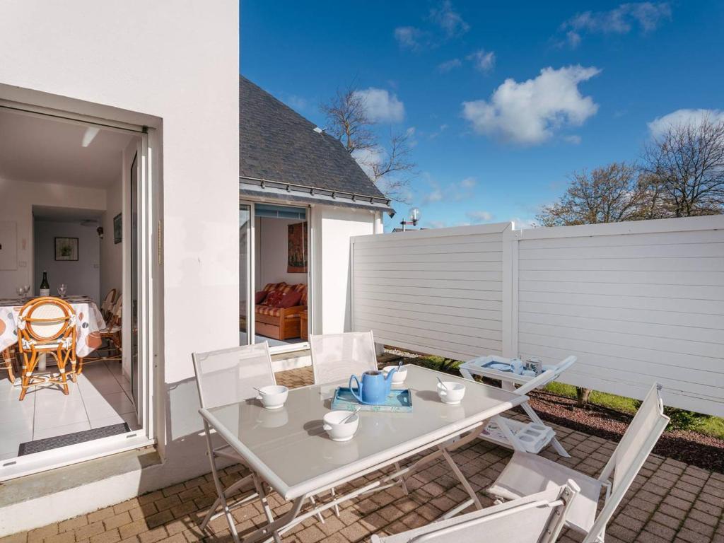 une table blanche et des chaises sur une terrasse dans l'établissement Carnac: Appartement 3P avec Piscine Chauffée, Terrasse et Parking, à 1 km de la Plage - FR-1-477-245, à Carnac