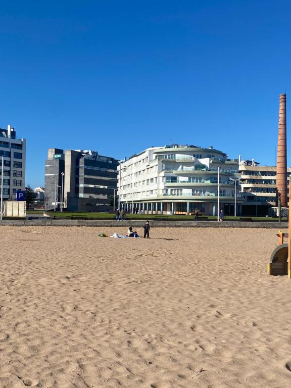 um grupo de pessoas sentadas na praia em Poniente Beach em Gijón