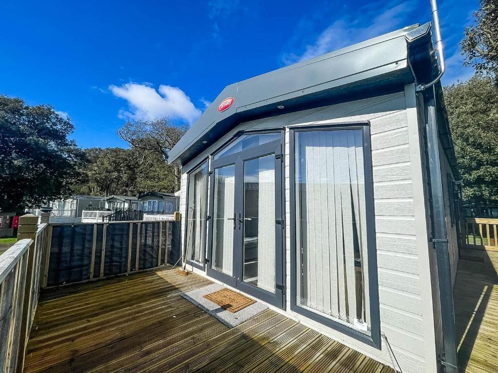a tiny house is sitting on a deck at Beautiful Caravan With Decking And Wifi At Azure Sea, Suffolk Ref 32025az in Lowestoft