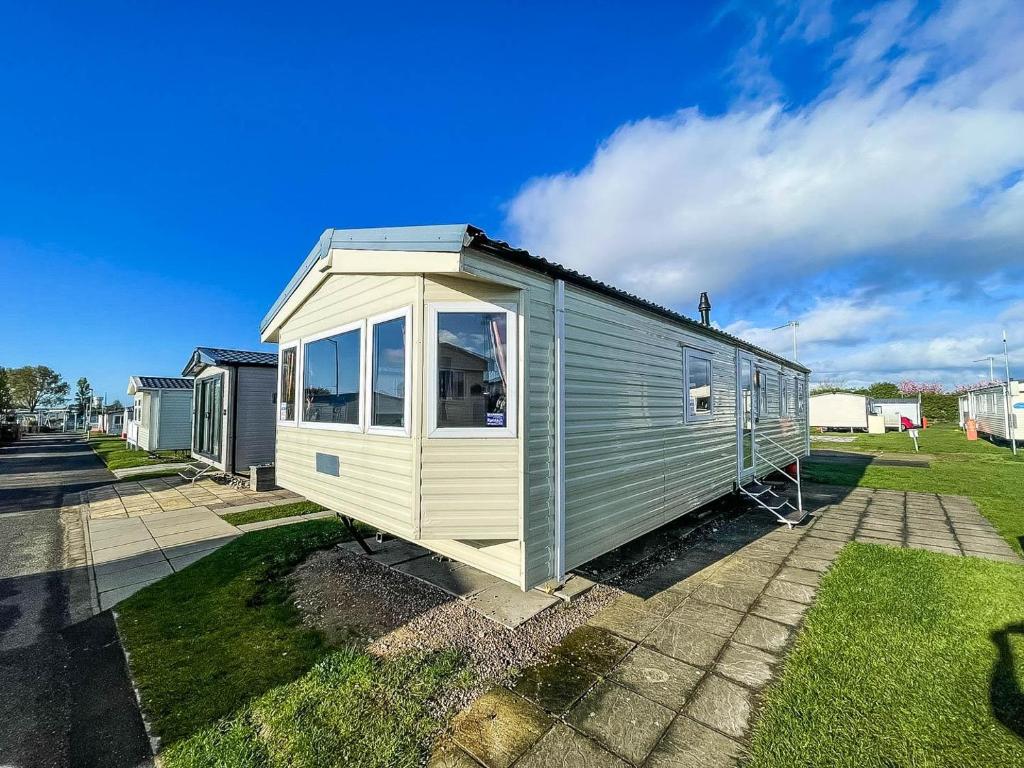 a tiny house is sitting on the grass at Lovely 8 Berth Caravan At California Cliffs Nearby Scratby Beach Ref 50060e in Great Yarmouth