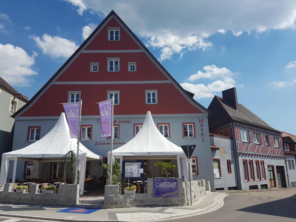 a large red and white building with tents in front of it at Seebauer-Hotel Die Ente von Wassertrüdingen in Wassertrüdingen