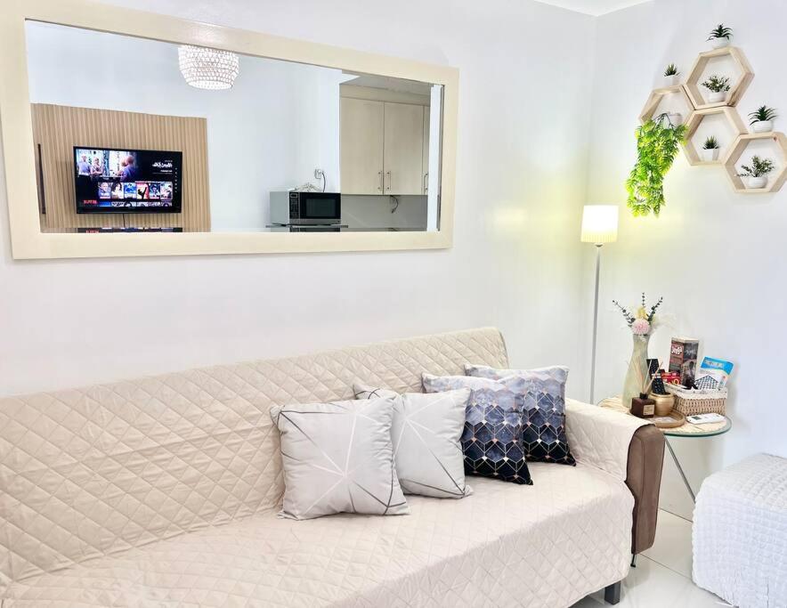 una sala de estar con un sofá blanco con almohadas en Tropical 1BR Unit at Sea Residences B MOA nr NAIA, en Manila