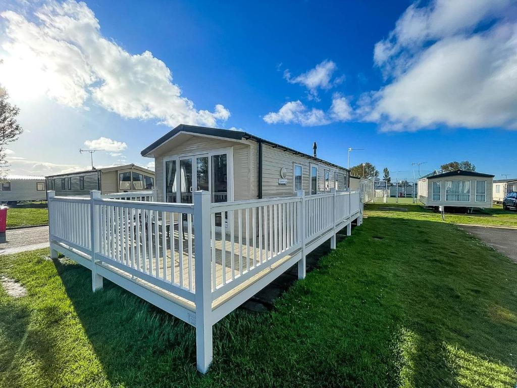 a mobile home with a white deck on the grass at Lovely 6 Berth, Dog Friendly Caravan For Hire In Norfolk Ref 50011ae in Great Yarmouth