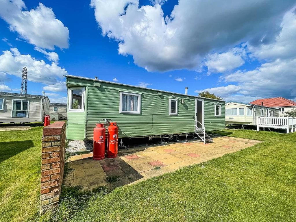 a green tiny house with two red fire hydrants at Great Caravan At Valley Farm Holiday Park, Essex Ref 46583v in Great Clacton