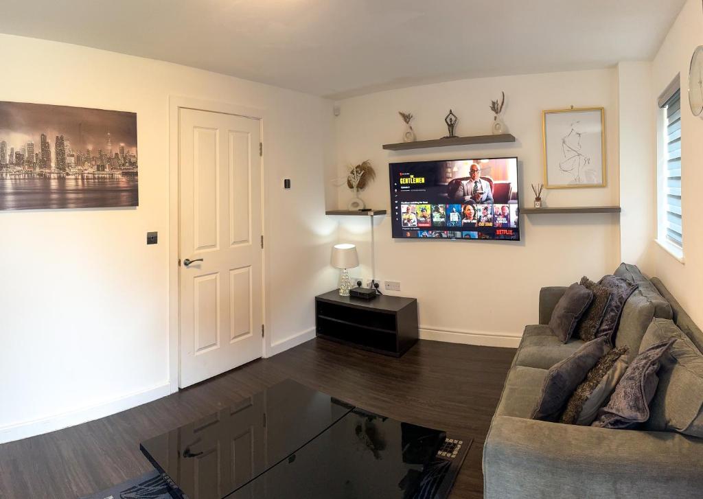 a living room with a couch and a flat screen tv at Amersham Park Apartment in Manchester