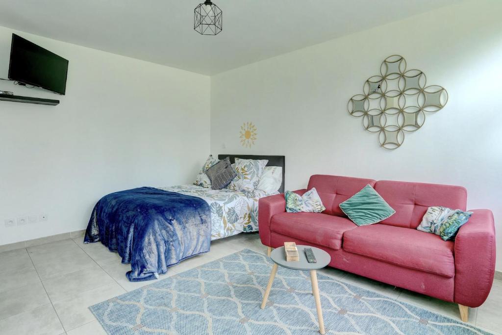 ein Wohnzimmer mit einem roten Sofa und einem Bett in der Unterkunft La citadine - Abondant in Abondant