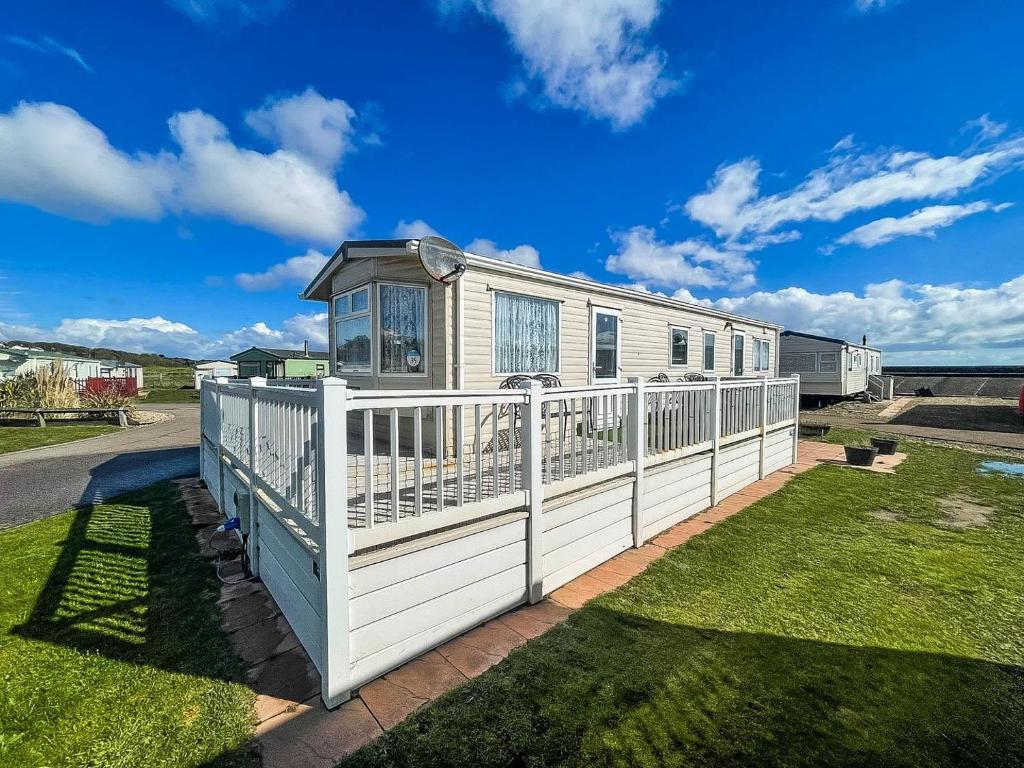 a house with a white fence on a yard at Ref 40035nd - Superb Caravan With Decking Free Wifi At North Denes Holiday Park in Lowestoft