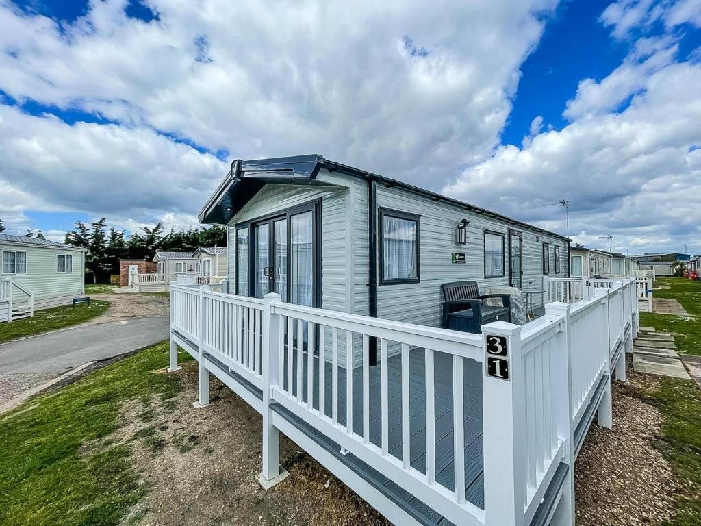 ein winziges Haus mit einer weißen Veranda und einem Zaun in der Unterkunft Stunning 6 Berth Caravan At Suffolk Sands Holiday Park Ref 45031g in Felixstowe