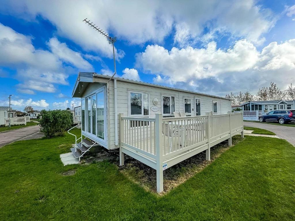 a blue house on a grassy field with a windmill at Beautiful Caravan With Decking At California Cliffs In Scratby Ref 50052l in Great Yarmouth