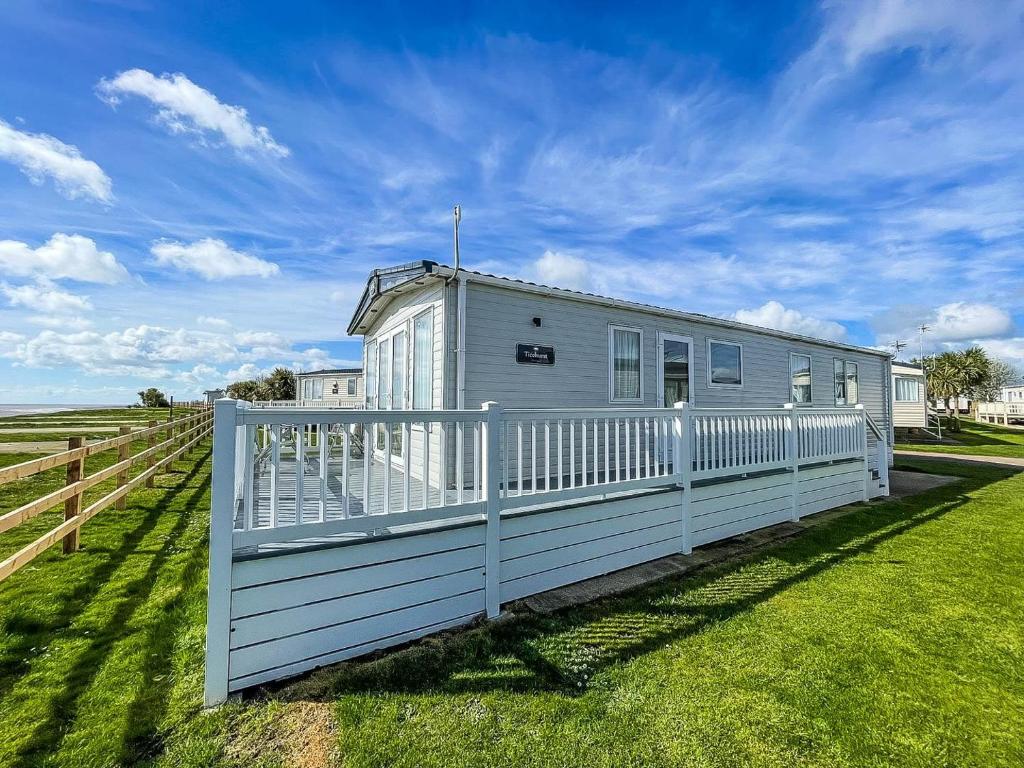 una casa blanca con una valla en un campo en Beautiful 6 Berth Caravan With Full Sea Views For Hire In Suffolk Ref 68002cr en Lowestoft