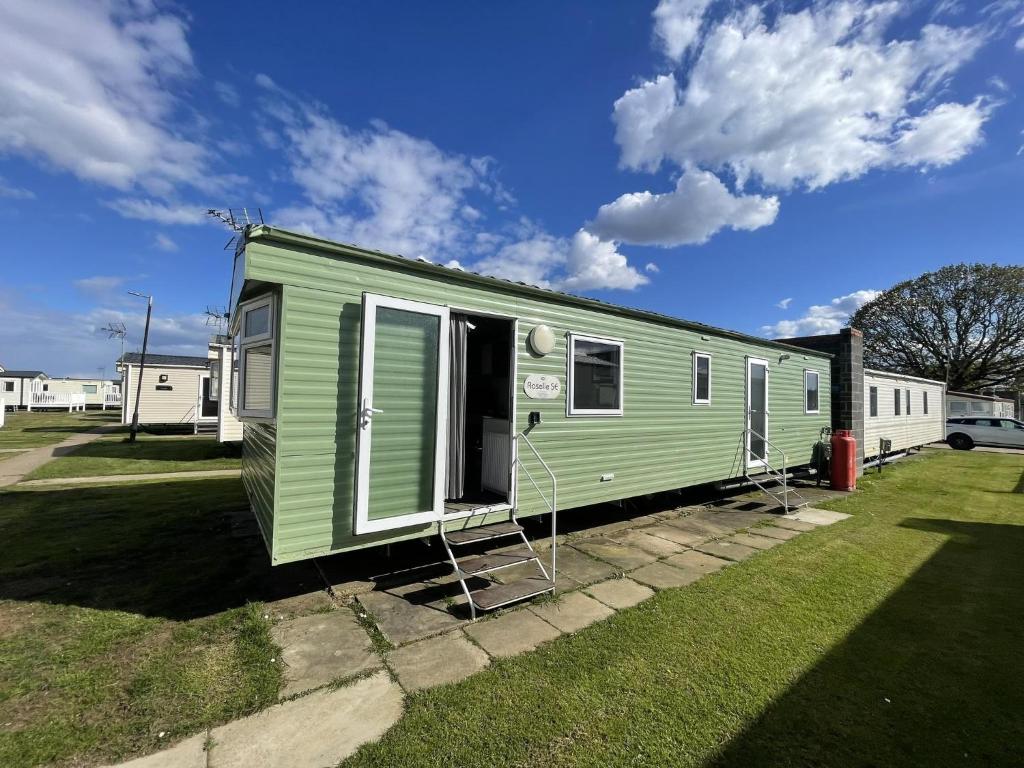 a green trailer with two chairs in a yard at Great 8 Berth Caravan At Highfield Grange, Clacton-on-sea Ref 26214o in Clacton-on-Sea