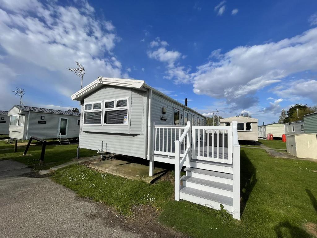 a white tiny house with a white fence at Wonderful 8 Berth Caravan With Wi-fi And Decking At Seawick, Ref 27023sw in Clacton-on-Sea