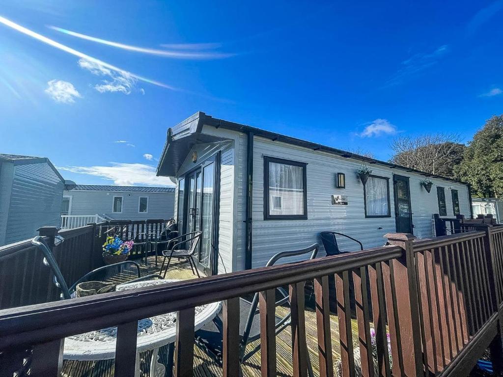 a blue tiny house with a wooden deck at Beautiful Caravan For Hire With A Partial Sea View In Suffolk Ref 32042az in Lowestoft