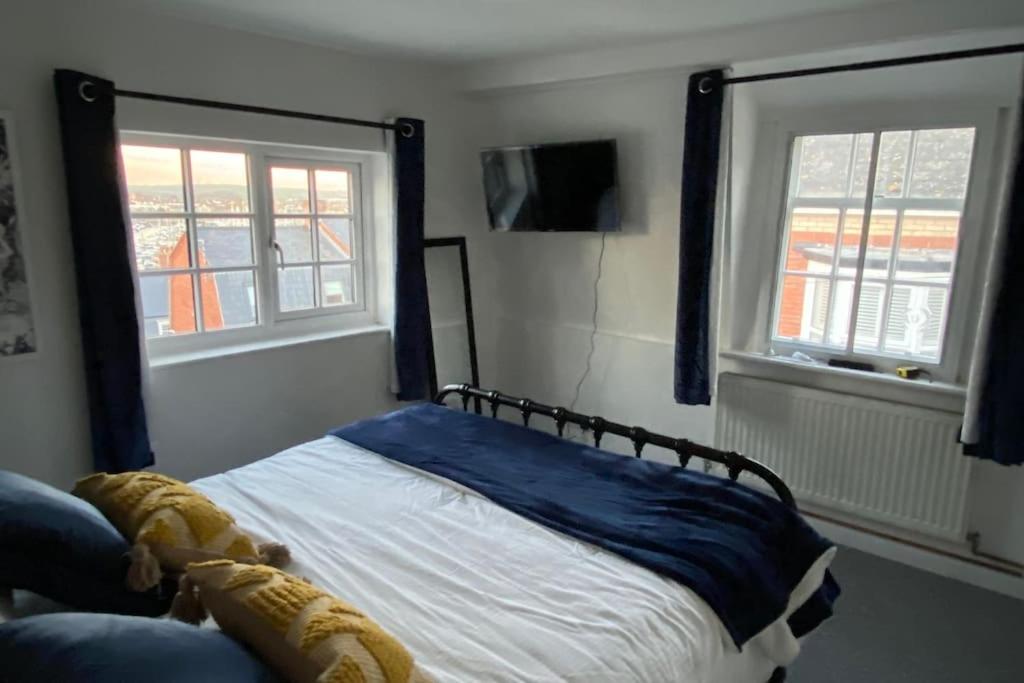 1 dormitorio con 1 cama y 2 ventanas en SNUGGLES en Weymouth