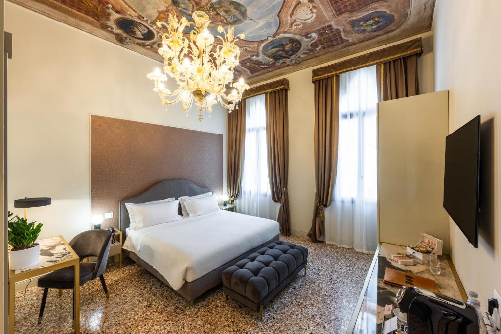 Habitación de hotel con cama y lámpara de araña. en Hotel Palazzina Sardi en Venecia